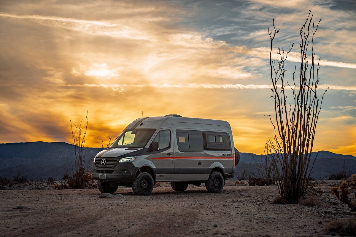 Van parked in the desert under a golden sunset sky